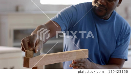 Smoothing wooden board by man wearing blue t-shirt in home workshop, with hand plane, copy space Smoothing wooden board by man wearing blue t-shirt in home workshop, with hand plane, copy space 139425166