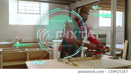 Carpenter wearing safety glasses sanding plank with red orbital sander in workshop, with AR overlay Carpenter wearing safety glasses sanding plank with red orbital sander in workshop, with AR overlay 139425167