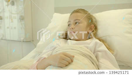 Lying girl wearing gown resting on hospital bed in ward, with blanket pillow monitoring panel 139425171