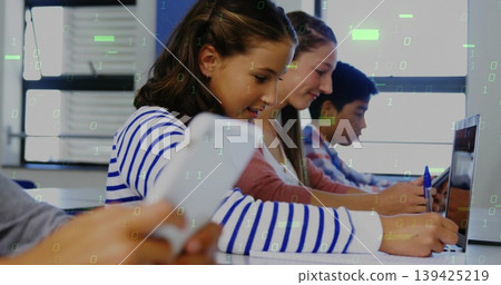 Writing and typing teenage students at computer lab with laptops, notebooks and binary code overlay 139425219