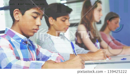 Writing four teenage students focusing on paper at classroom desk, with blue pens Writing four teenage students focusing on paper at classroom desk, with blue pens 139425222