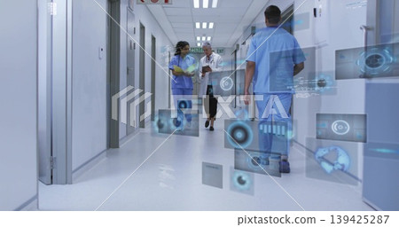 Walking staff in scrubs and coat holding clipboard in hospital corridor, with holographic displays Walking staff in scrubs and coat holding clipboard in hospital corridor, with holographic displays 139425287