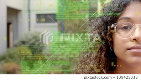 Teenager with clear-framed glasses and hoop earring analyzing code overlay in courtyard, copy space 139425338