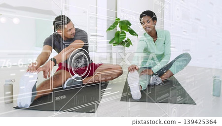Stretching partners touching toes in fitness studio, with black mats and digital overlays 139425364