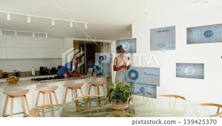 Interacting woman manipulating blue holographic panels in kitchen, with laptop, copy space Interacting woman manipulating blue holographic panels in kitchen, with laptop, copy space 139425370