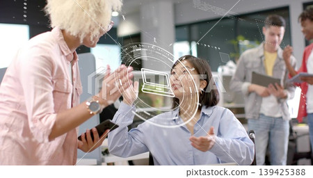 Seated woman in blue shirt gesturing toward holographic laptop icon in modern office 139425388