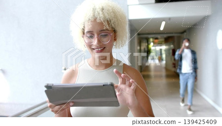 Tapping tablet woman in tank top and glasses while man sipping coffee cup in glass-railed corridor 139425409