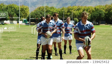 Rugby players walking on grass pitch in striped jerseys with rugby balls and goalposts Rugby players walking on grass pitch in striped jerseys with rugby balls and goalposts 139425412