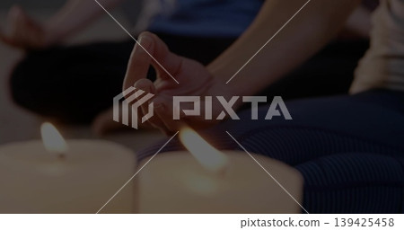 Showing woman's hand forming mudra on striped leggings and yoga mat at yoga studio, with candles Showing woman's hand forming mudra on striped leggings and yoga mat at yoga studio, with candles 139425458