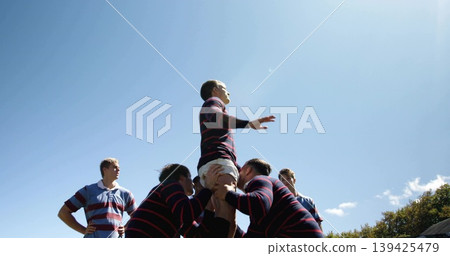 Lifting six rugby players in lineout on grassy field, wearing striped jerseys, shorts and cleats 139425479