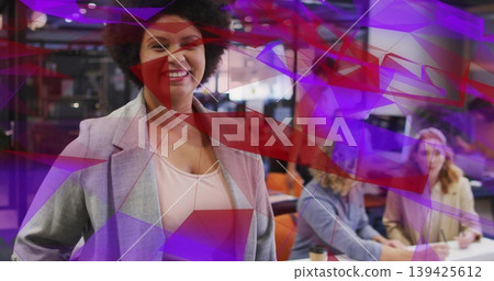 Standing woman wearing gray blazer, smiling in coworking office with laptops, coffee cups Standing woman wearing gray blazer, smiling in coworking office with laptops, coffee cups 139425612
