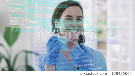 Removing woman in blue scrubs adjusting blue surgical mask in clinic reception, with code overlay 139425664