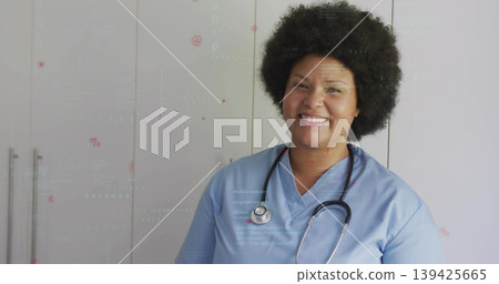 Smiling nurse standing in clinic, with blue scrubs, stethoscope and cabinet handles, copy space 139425665
