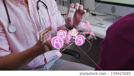 Doctor wearing pink shirt, stethoscope, holding pill bottle above network in office, copy space 139425685