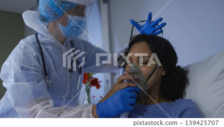 Healthcare provider in protective gown positioning oxygen mask on patient in hospital room 139425707