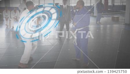 Sparring duo wearing gis and white belts throwing kicks and punches in dojo, with mats, windows 139425750