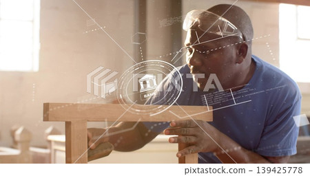 Mature carpenter in safety goggles sanding stool in workshop, showing bank graphics, copy space Mature carpenter in safety goggles sanding stool in workshop, showing bank graphics, copy space 139425778