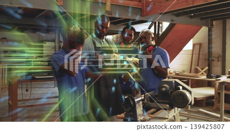 Inspecting wooden block, four craftsmen wearing hearing protectors working beside lathe in woodshop Inspecting wooden block, four craftsmen wearing hearing protectors working beside lathe in woodshop 139425807