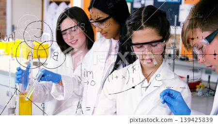 Pouring yellow liquid from cylinder into test tube students at science bench, with pipette beakers 139425839