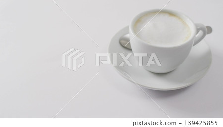Featuring white ceramic cup holding frothy coffee in kitchen, with saucer and teaspoon, copy space Featuring white ceramic cup holding frothy coffee in kitchen, with saucer and teaspoon, copy space 139425855