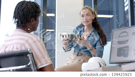 Female engineer explaining holographic interface in office, with smartphone, VR headset and monitor Female engineer explaining holographic interface in office, with smartphone, VR headset and monitor 139425925