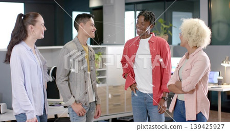 Standing group of four colleagues chatting in open-plan office, with desks, chairs and laptops Standing group of four colleagues chatting in open-plan office, with desks, chairs and laptops 139425927