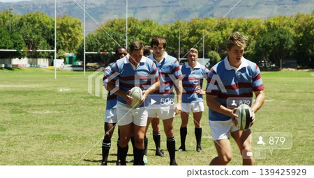 Striding seven rugby players wearing striped jerseys, white shorts on grass pitch, with rugby balls Striding seven rugby players wearing striped jerseys, white shorts on grass pitch, with rugby balls 139425929