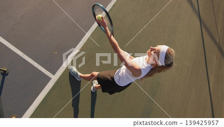Tossing woman raising racket on outdoor tennis court, with ball, sportswear, lines, copy space Tossing woman raising racket on outdoor tennis court, with ball, sportswear, lines, copy space 139425957