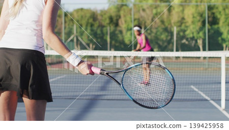 Woman in white top, black skirt swinging racket on blue court, with net, lines, copy space Woman in white top, black skirt swinging racket on blue court, with net, lines, copy space 139425958
