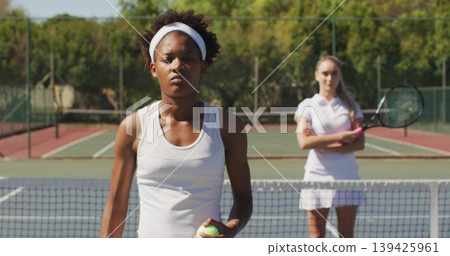 Gripping tennis ball, player in white top preparing serve on outdoor court, with net and racquet 139425961