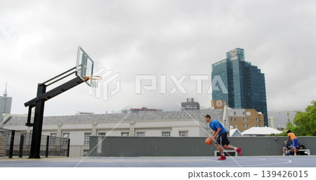 Dribbling basketball player in blue shirt, black shorts heading to left rooftop hoop, copy space Dribbling basketball player in blue shirt, black shorts heading to left rooftop hoop, copy space 139426015