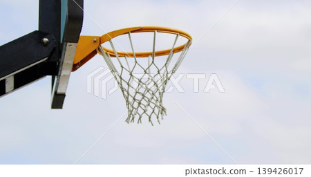 Showing basketball hoop with orange rim and white net at outdoor court left, copy space 139426017