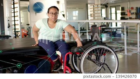 Practicing woman wearing glasses in sportswear moving from padded bench to red wheelchair in rehab Practicing woman wearing glasses in sportswear moving from padded bench to red wheelchair in rehab 139426070