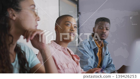 Shaved head woman in pink shirt and colleagues discussing at conference table, laptop map overlay Shaved head woman in pink shirt and colleagues discussing at conference table, laptop map overlay 139426253