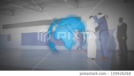 Grappling pair of martial artists practicing judo on blue mats at gymnasium, with digital globe 139426268