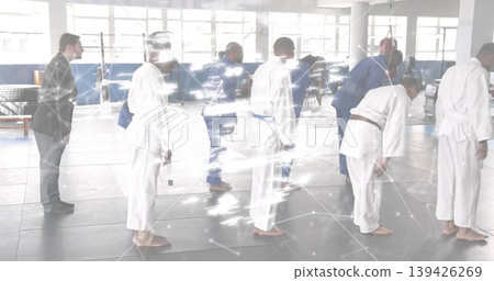 Coach wearing suit and group in gis lining up facing right in dojo, with colored belts Coach wearing suit and group in gis lining up facing right in dojo, with colored belts 139426269
