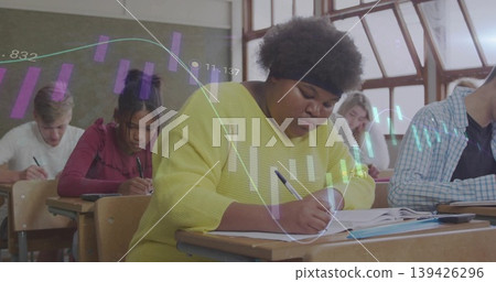 Writing African American student in yellow top taking notes in classroom, with projected bar charts Writing African American student in yellow top taking notes in classroom, with projected bar charts 139426296