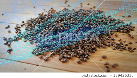 Displaying roasted coffee beans scattering across wooden tabletop, with turquoise digital artifacts Displaying roasted coffee beans scattering across wooden tabletop, with turquoise digital artifacts 139426333