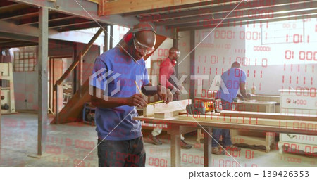 Marking wooden plank male carpenter wearing safety goggles, earmuffs at workshop, with pencil Marking wooden plank male carpenter wearing safety goggles, earmuffs at workshop, with pencil 139426353
