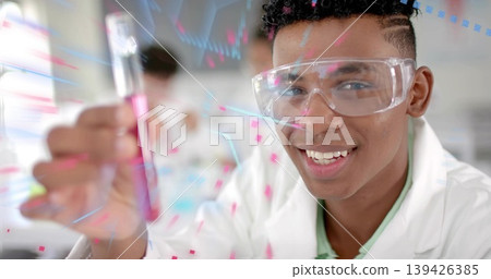 African American teen wearing lab coat holding pink test tube at school lab, with digital overlay African American teen wearing lab coat holding pink test tube at school lab, with digital overlay 139426385