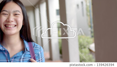 Smiling schoolgirl wearing blue shirt with backpack strap in campus walkway, cloud icon, copy space Smiling schoolgirl wearing blue shirt with backpack strap in campus walkway, cloud icon, copy space 139426394