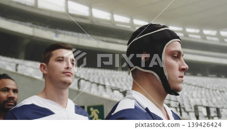 Standing rugby players wearing headgear and blue-white jerseys in tunnel near exit sign, copy space Standing rugby players wearing headgear and blue-white jerseys in tunnel near exit sign, copy space 139426424