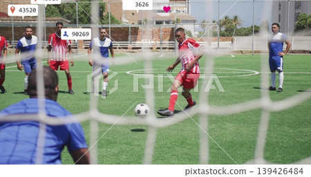 Player in red-white kit kicking ball toward net on turf, goalkeeper and social overlay, copy space Player in red-white kit kicking ball toward net on turf, goalkeeper and social overlay, copy space 139426484