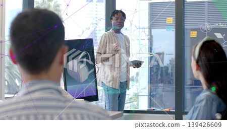 Standing man holding tablet and gesturing in modern office, VR monitor, glass board, striped shirt Standing man holding tablet and gesturing in modern office, VR monitor, glass board, striped shirt 139426609
