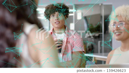 Holding male in striped shirt sipping disposable cup at office table, laptop and turquoise overlay 139426623