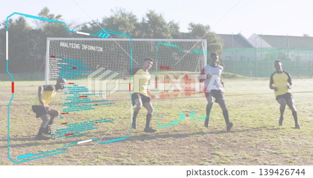 Standing soccer players wearing jerseys analyzing digital overlay on park pitch, with goal net 139426744