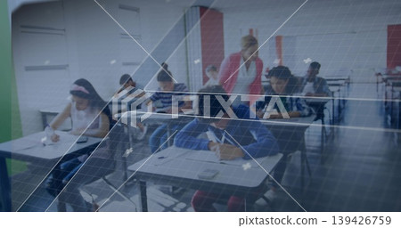 Supervising teacher in red observing students writing papers at classroom desks with calculator 139426759