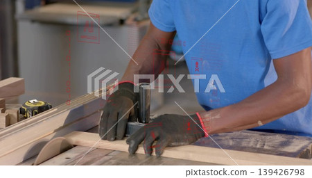 Cutting plank on table saw in woodshop, woodworker wearing gloves with push block, copy space Cutting plank on table saw in woodshop, woodworker wearing gloves with push block, copy space 139426798