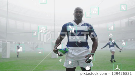 Rugby player wearing navy jersey holding rugby ball on pitch by padded goalposts with data overlays Rugby player wearing navy jersey holding rugby ball on pitch by padded goalposts with data overlays 139426821
