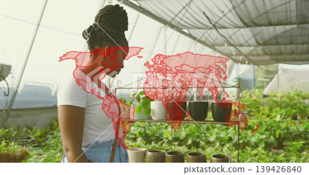 Inspecting woman wearing denim apron tending pots in greenhouse nursery, metal shelf, copy space Inspecting woman wearing denim apron tending pots in greenhouse nursery, metal shelf, copy space 139426840